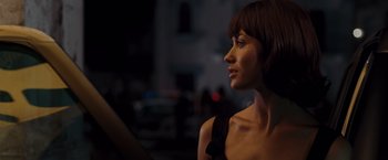 Movie still from “Quantum of Solace” (2008), directed by Marc Forster – A beautiful woman with short brown hair wearing a black dress; Close Up shot, Over the shoulder angle