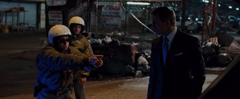 Movie still from “Quantum of Solace” (2008), directed by Marc Forster – A man in a suit and a helmet is holding a gun; Medium shot, Over the shoulder angle