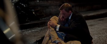 Movie still from “Quantum of Solace” (2008), directed by Marc Forster – A man in a business suit is hugging another man; Medium shot, High angle