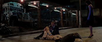 Movie still from “Quantum of Solace” (2008), directed by Marc Forster – A man and a woman sitting on the ground in front of a fence; Wide shot, High angle