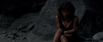 Movie still from “Quantum of Solace” (2008), directed by Marc Forster – A woman sitting on the ground in front of a rock wall; Medium shot, High angle