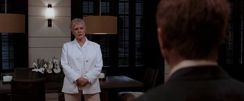 Movie still from “Quantum of Solace” (2008), directed by Marc Forster – An older woman standing in front of a man in front of a mirror; Medium shot, Over the shoulder angle