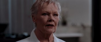 Movie still from “Quantum of Solace” (2008), directed by Marc Forster – An older woman with short white hair looking at the camera; Close Up shot, Low angle
