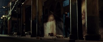 Movie still from “Quantum of Solace” (2008), directed by Marc Forster – A dog laying on the ground next to an open door; Wide shot, Low angle