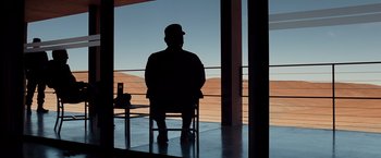 Movie still from “Quantum of Solace” (2008), directed by Marc Forster – A man sitting on a chair in front of a window; Wide shot, Over the shoulder angle