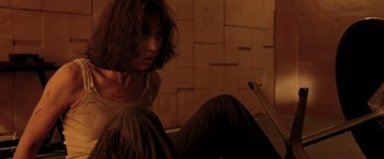Movie still from “Quantum of Solace” (2008), directed by Marc Forster – A woman sitting on the ground in a room; Medium shot, Low angle