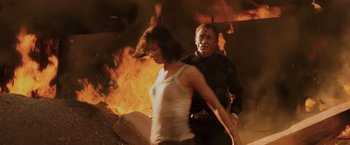 Movie still from “Quantum of Solace” (2008), directed by Marc Forster – A man and a woman walking in front of a fire; Medium shot, Low angle