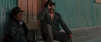 Movie still from “Quantum of Solace” (2008), directed by Marc Forster – A man sitting on the ground with a bottle of wine; Medium shot, Low angle