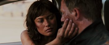 Movie still from “Quantum of Solace” (2008), directed by Marc Forster – A woman looking at a man who is touching his face; Close Up shot, Over the shoulder angle