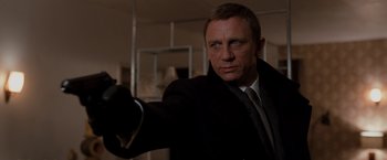 Movie still from “Quantum of Solace” (2008), directed by Marc Forster – A man in a suit and tie holding a gun; Close Up shot, Over the shoulder angle