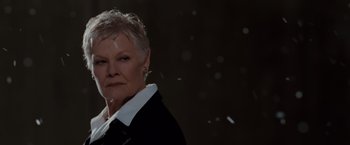 Movie still from “Quantum of Solace” (2008), directed by Marc Forster – An older woman with short hair wearing a black jacket; Close Up shot, Low angle