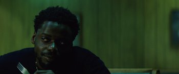 Movie still from “Queen & Slim” (2019), directed by Melina Matsoukas – A man sitting in front of a green wall; Close Up shot, Over the shoulder angle