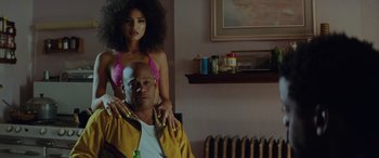 Movie still from “Queen & Slim” (2019), directed by Melina Matsoukas – A man sitting on a chair next to a woman in a pink bikini; Medium shot, Low angle