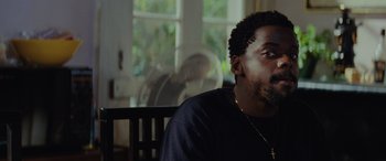 Movie still from “Queen & Slim” (2019), directed by Melina Matsoukas – A person sitting in a room; Close Up shot, Over the shoulder angle