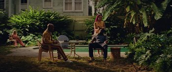 Movie still from “Queen & Slim” (2019), directed by Melina Matsoukas – A group of people sitting in a yard; Wide shot, Over the shoulder angle