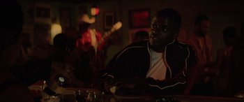 Movie still from “Queen & Slim” (2019), directed by Melina Matsoukas – A man sitting at a table in front of a guitar; Medium shot, Over the shoulder angle