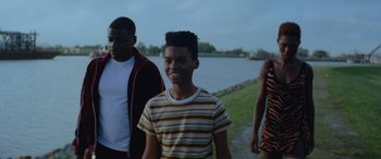 Movie still from “Queen & Slim” (2019), directed by Melina Matsoukas – A group of young people standing next to a body of water; Medium shot, Over the shoulder angle
