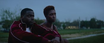 Movie still from “Queen & Slim” (2019), directed by Melina Matsoukas – A man and a woman sitting next to each other on the grass; Medium shot, Over the shoulder angle