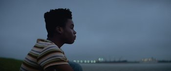 Movie still from “Queen & Slim” (2019), directed by Melina Matsoukas – A young man sitting on the beach at night; Close Up shot, Low angle