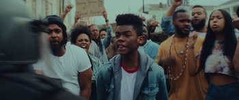 Movie still from “Queen & Slim” (2019), directed by Melina Matsoukas – A group of people protesting in the middle of the street; Close Up shot, Over the shoulder angle