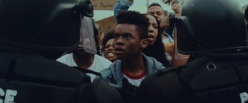 Movie still from “Queen & Slim” (2019), directed by Melina Matsoukas – A group of young people gathered together in the street; Close Up shot, Over the shoulder angle