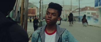 Movie still from “Queen & Slim” (2019), directed by Melina Matsoukas – A young black man standing on the side of the street; Close Up shot, Over the shoulder angle