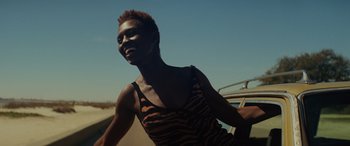 Movie still from “Queen & Slim” (2019), directed by Melina Matsoukas – A woman riding a motorcycle down a street; Close Up shot, Low angle