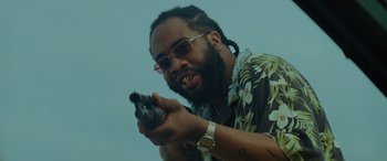 Movie still from “Queen & Slim” (2019), directed by Melina Matsoukas – A man holding a gun while wearing sunglasses and a hawaiian shirt; Close Up shot, Low angle