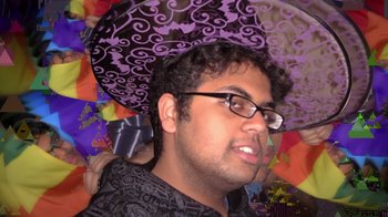Movie still from “Queenmaker: The Making of an It Girl” (2023), directed by Zackary Drucker – A man with glasses is holding an umbrella; Close Up shot, Overhead angle