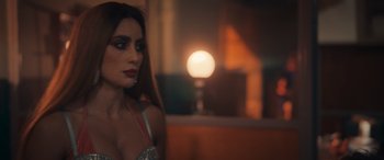 Movie still from “Queens on the Run” (2023), directed by Jorge Macaya – A woman in a silver dress is standing in front of a mirror; Close Up shot, Over the shoulder angle