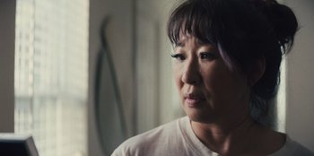 Movie still from “Quiz Lady” (2023), directed by Jessica Yu – An older asian woman with purple hair looking off into the distance; Close Up shot, Over the shoulder angle