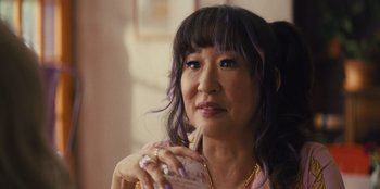 Movie still from “Quiz Lady” (2023), directed by Jessica Yu – A woman with purple hair is holding a cell phone; Close Up shot, Over the shoulder angle