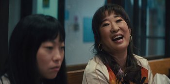 Movie still from “Quiz Lady” (2023), directed by Jessica Yu – A woman laughing while sitting next to another woman; Close Up shot, Over the shoulder angle