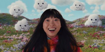 Movie still from “Quiz Lady” (2023), directed by Jessica Yu – A woman with long black hair smiles in front of a field of flowers; Close Up shot, Overhead angle