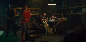 Movie still from “Quiz Lady” (2023), directed by Jessica Yu – A group of people sitting around a table with a dog; Wide shot, Over the shoulder angle