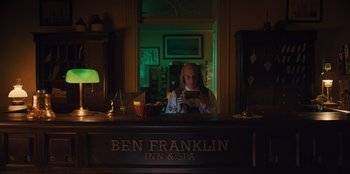 Movie still from “Quiz Lady” (2023), directed by Jessica Yu – A man sitting at the front of a room looking at his cell phone; Medium shot, Low angle