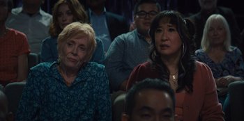 Movie still from “Quiz Lady” (2023), directed by Jessica Yu – A group of people sitting in front of each other; Close Up shot, Over the shoulder angle