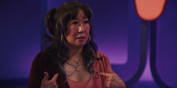 Movie still from “Quiz Lady” (2023), directed by Jessica Yu – An asian woman is pointing to her face; Close Up shot, Over the shoulder angle