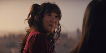 Movie still from “Quiz Lady” (2023), directed by Jessica Yu – A person with long hair; Close Up shot, Over the shoulder angle