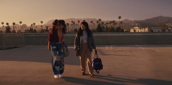 Movie still from “Quiz Lady” (2023), directed by Jessica Yu – Two young women are walking on the sidewalk; Wide shot, Low angle