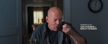 A bald man is eating something while sitting at a table