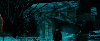 Movie still from “RED” (2010), directed by Robert Schwentke – A person standing in front of a house in the snow; Wide shot, High angle