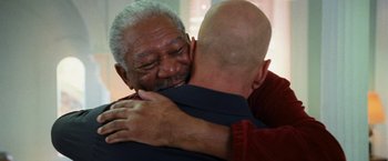 Movie still from “RED” (2010), directed by Robert Schwentke – Two older men hugging each other in front of a window; Close Up shot, Low angle