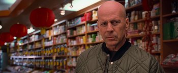 Movie still from “RED” (2010), directed by Robert Schwentke – A man with a bald head standing in front of shelves of drinks; Close Up shot, Over the shoulder angle