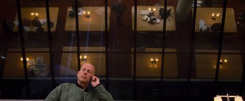 Movie still from “RED” (2010), directed by Robert Schwentke – A man sitting in front of a window talking on a cell phone; Wide shot, Overhead angle
