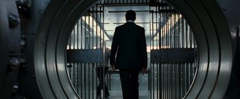 Movie still from “RED” (2010), directed by Robert Schwentke – A man in a black suit walking through a gate; Wide shot, Low angle