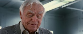Movie still from “RED” (2010), directed by Robert Schwentke – An older man with white hair looking down at his face; Close Up shot, Low angle