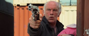 Movie still from “RED” (2010), directed by Robert Schwentke – An older man holding a gun in his right hand; Close Up shot, Low angle