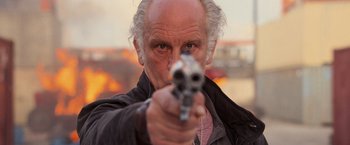 Movie still from “RED” (2010), directed by Robert Schwentke – An older man is holding a gun in his hand; Close Up shot, Low angle