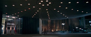 Movie still from “RED” (2010), directed by Robert Schwentke – A person walking in front of a building at night; Extreme Wide shot, Low angle